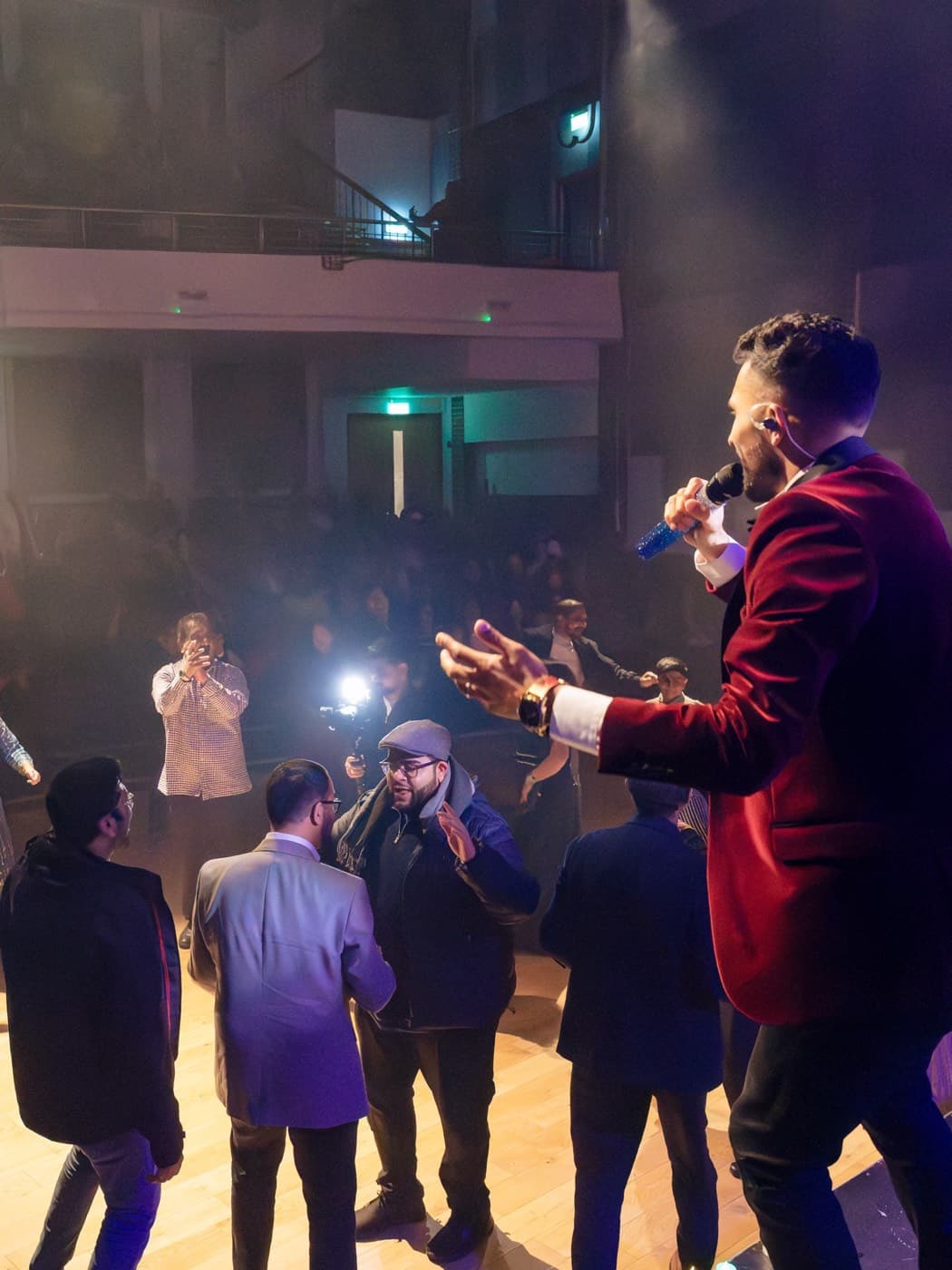 Paras performing from the stage in a red velvet jacket as the audience dances below